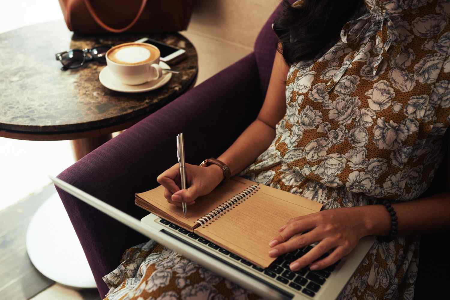 unrecognizable-woman-sitting-cafe-with-laptop-writing-notebook (1) women sitting at the cafe with laptop